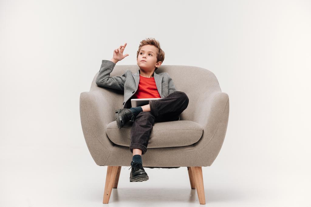 átgondolt elegáns kisfiú ül a karosszékben, tabletta - Fotó, kép