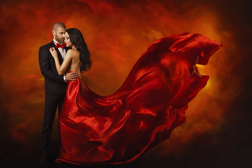 elegantes Paar, tanzende Frau im roten Kleid flatternd im Wind und Mann im schwarzen Anzug, Liebesporträt - Foto, Bild