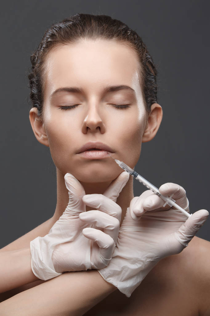 Retrato de mujer caucásica joven recibiendo inyección cosmética - Foto, imagen