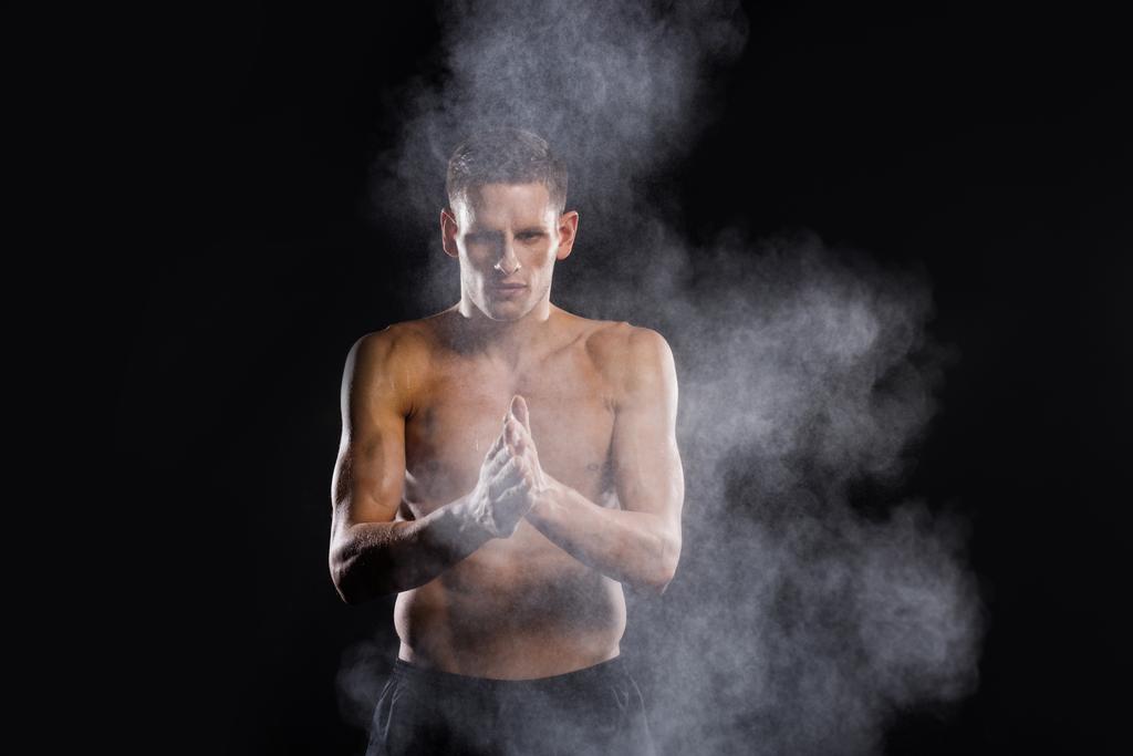camicia giovane sportivo che applica talco in polvere sulle mani e guardando la fotocamera su nero
 - Foto, immagini