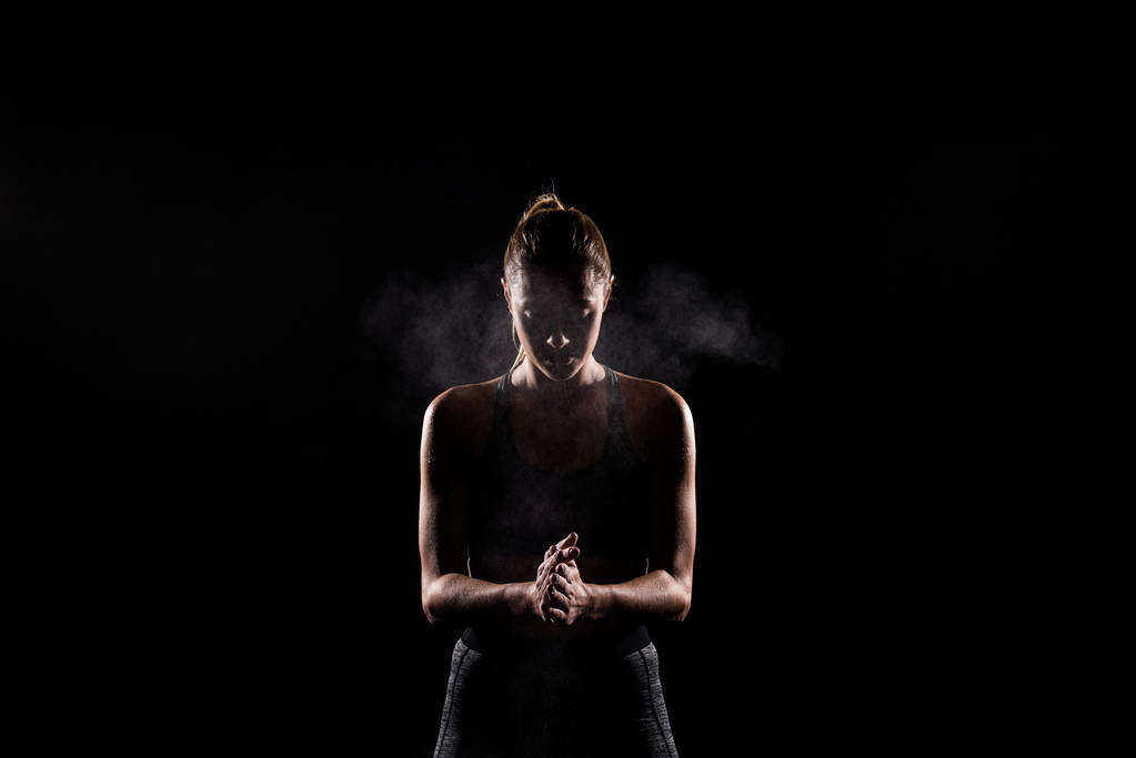 Silhouette einer Sportlerin, die Talkumpuder auf schwarze Hände aufträgt - Foto, Bild