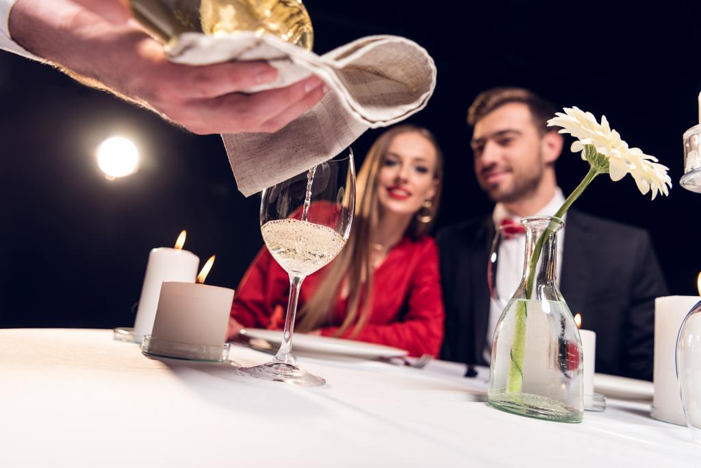 selektiver Fokus des Kellners, der Wein einschenkt, während das Paar ein romantisches Date im Restaurant hat - Foto, Bild