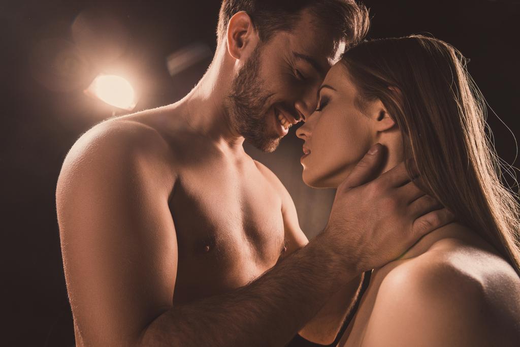 passionate couple hugging and smiling, on brown with back light - Photo, Image