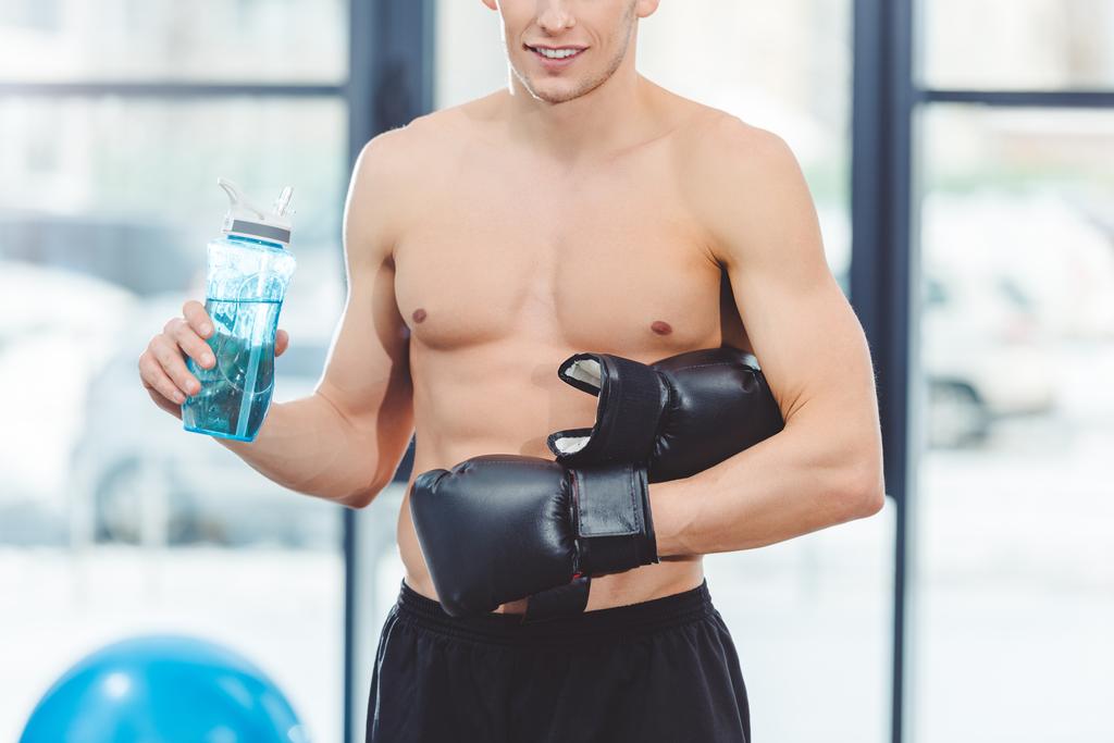 Boks eldivenleri içme suyu şişe içinde jimnastik salonu kas genç sporcu kadeh kırpılmış - Fotoğraf, Görsel