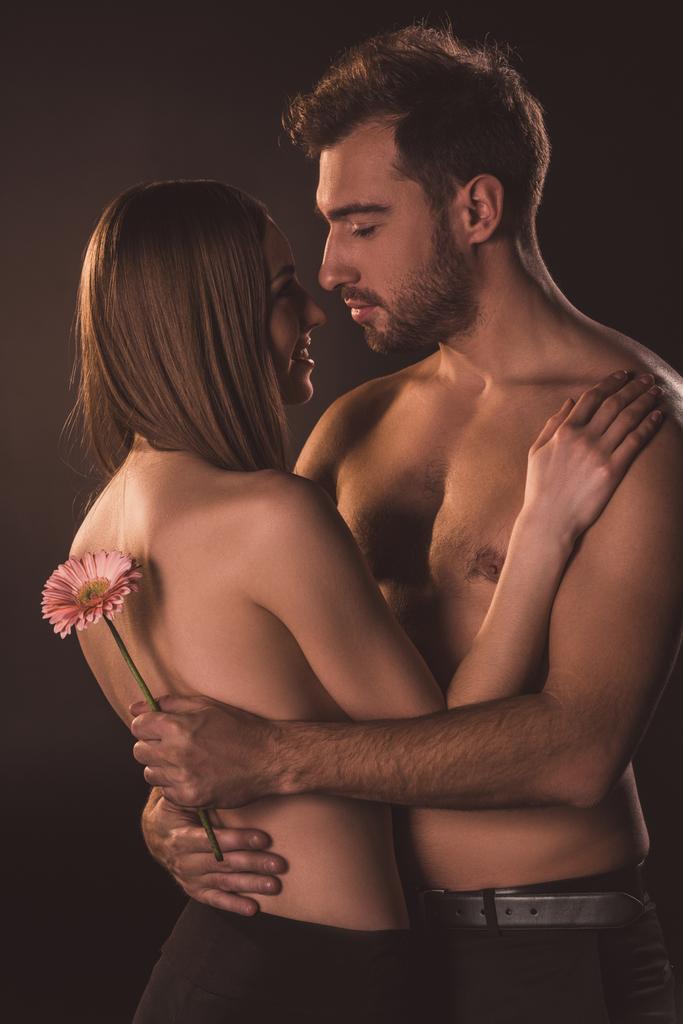tenera coppia che abbraccia e tiene il fiore, isolato su marrone
  - Foto, immagini