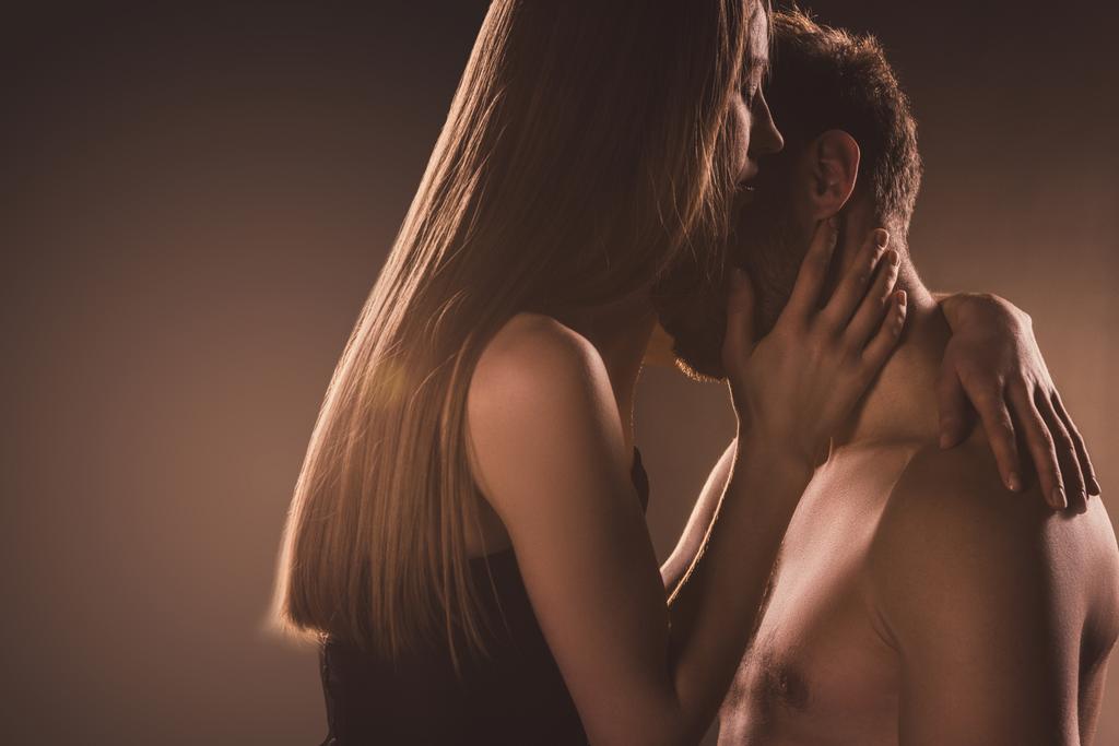 passionate couple embracing and kissing on brown with backlit - Photo, Image