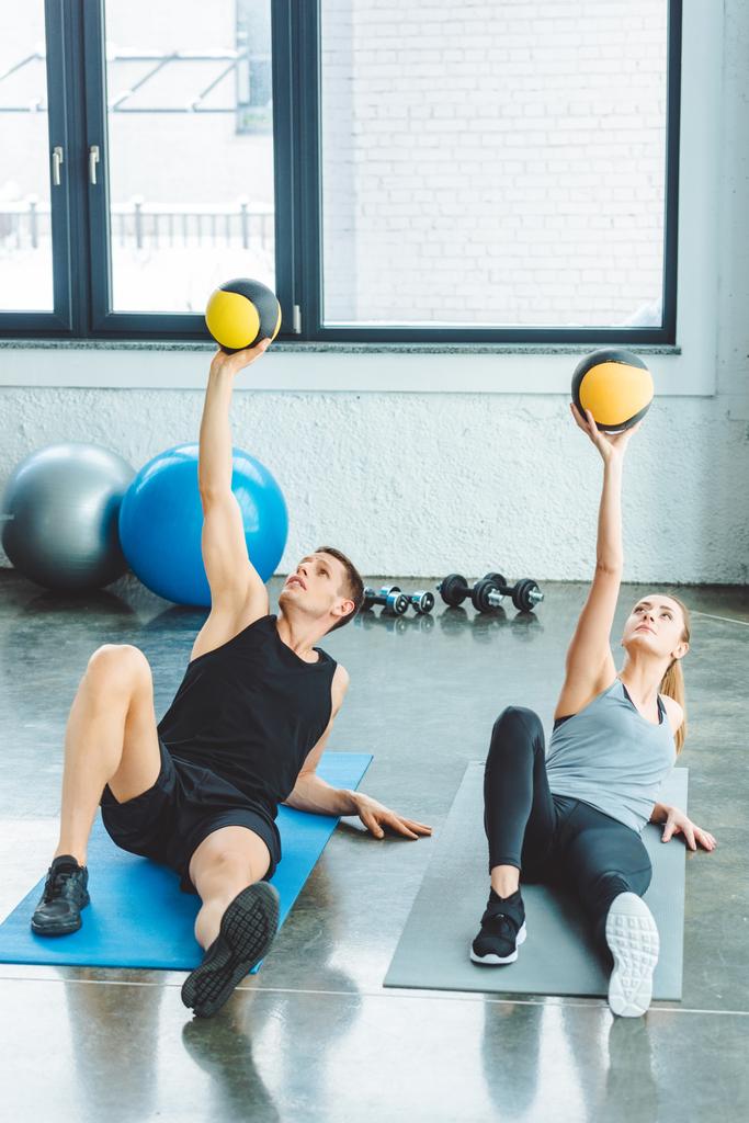 pareja atlética haciendo ejercicio con bolas juntos en el gimnasio
 - Foto, Imagen