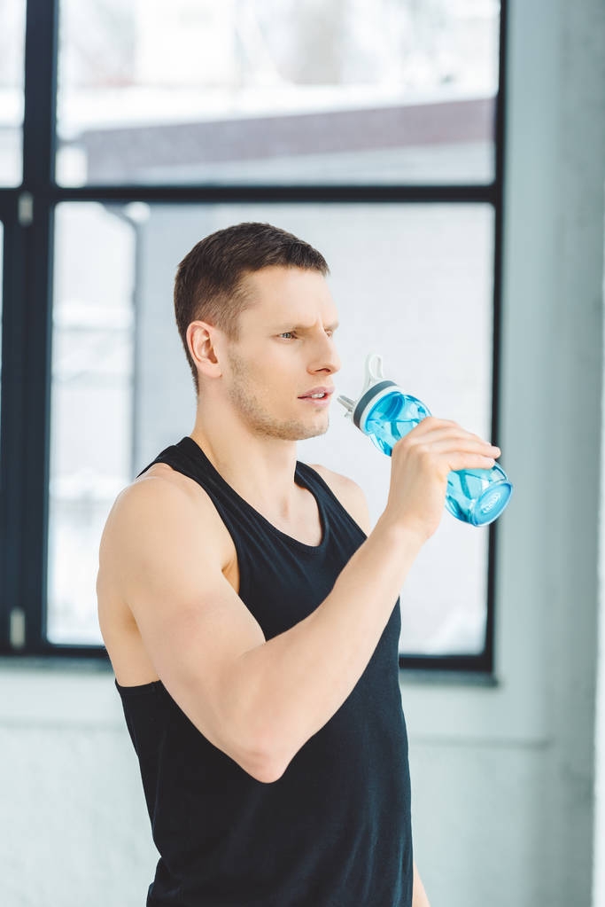 Портрет спортсмена, пьющего воду из спортивной бутылки после тренировки в тренажерном зале
 - Фото, изображение