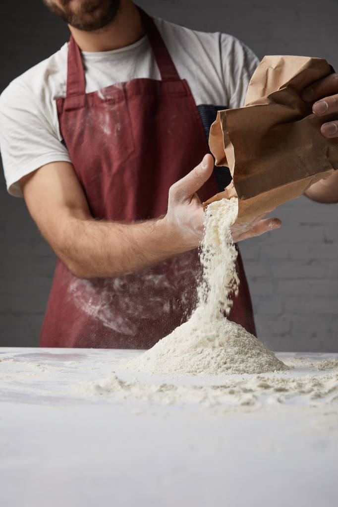 imagen recortada de chef vertiendo harina en la mesa
 - Foto, imagen