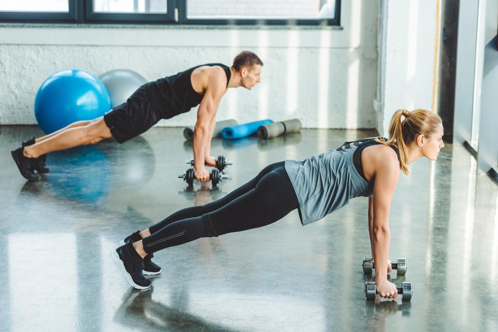 vue latérale du jeune homme et de la femme faisant de l'exercice avec des haltères dans la salle de gym
 - Photo, image