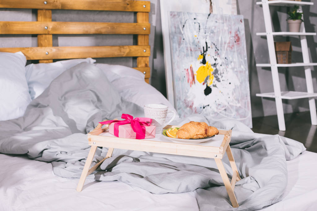 лоток с завтраком и коробка подарков на одеяло на кровати
 - Фото, изображение