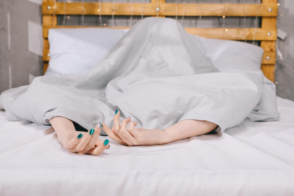 imagen recortada de chica con manicura acostado debajo de la manta en la cama
 - Foto, Imagen