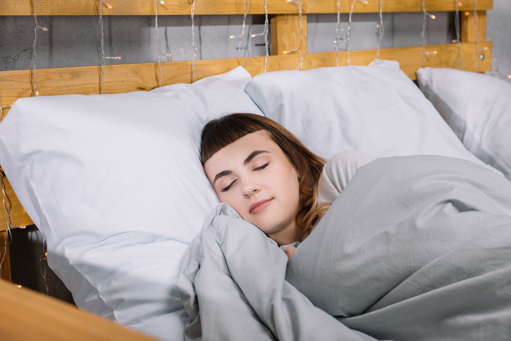 Yatak odasında beyaz yastıklar üzerinde uyuyan kız - Fotoğraf, Görsel