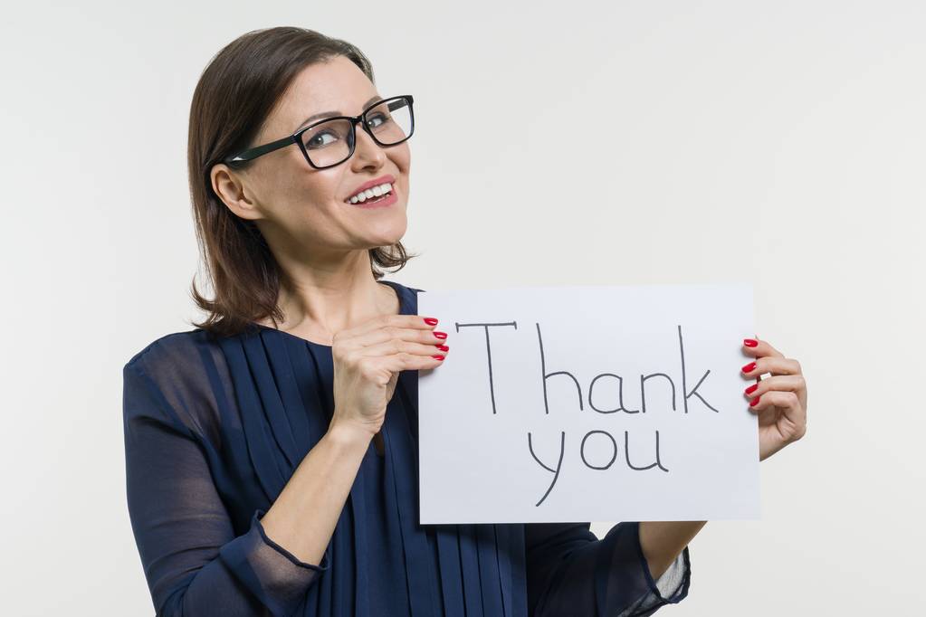 Happy businesswoman showing thanks. Holds the paper with the text thank you. - Photo, Image