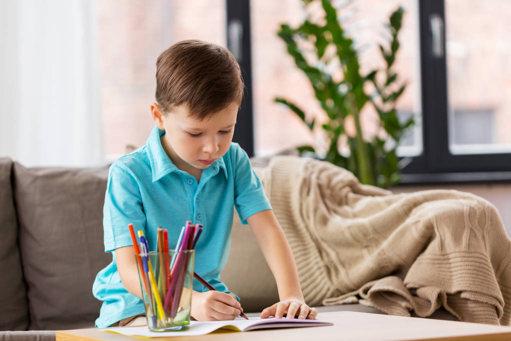 niño con cuaderno y lápices dibujando en casa
 - Foto, imagen