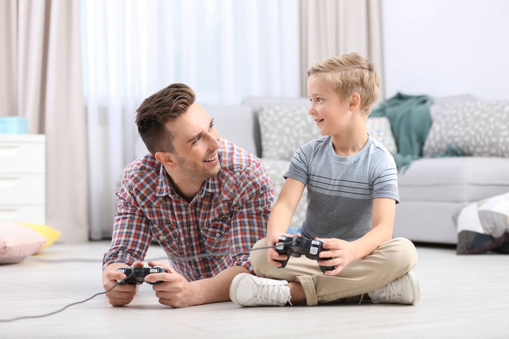 Cute little boy with father playing videogame at home - Photo, Image
