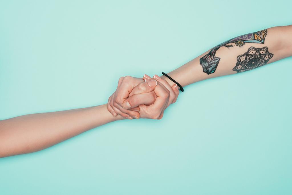 oříznuté shot žen drží za ruce, izolované na tyrkysové - Fotografie, Obrázek