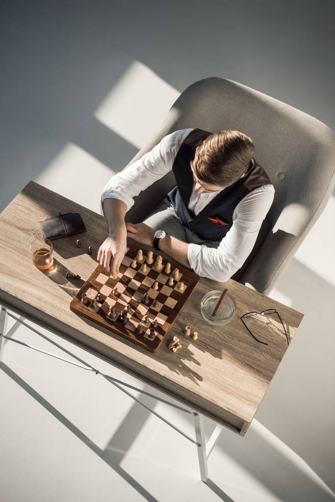 overhead view of businessman playing chess while drinking whisky and smoking cigar - Photo, Image