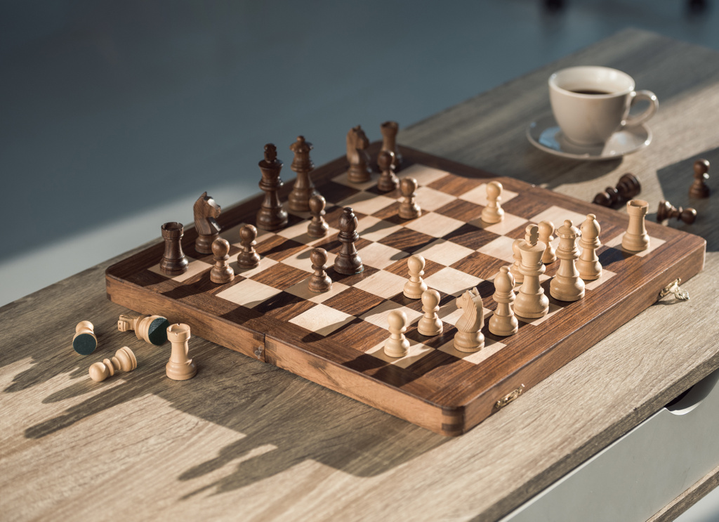 vista de primer plano del tablero de ajedrez con piezas y taza de café en la mesa de madera
 - Foto, Imagen