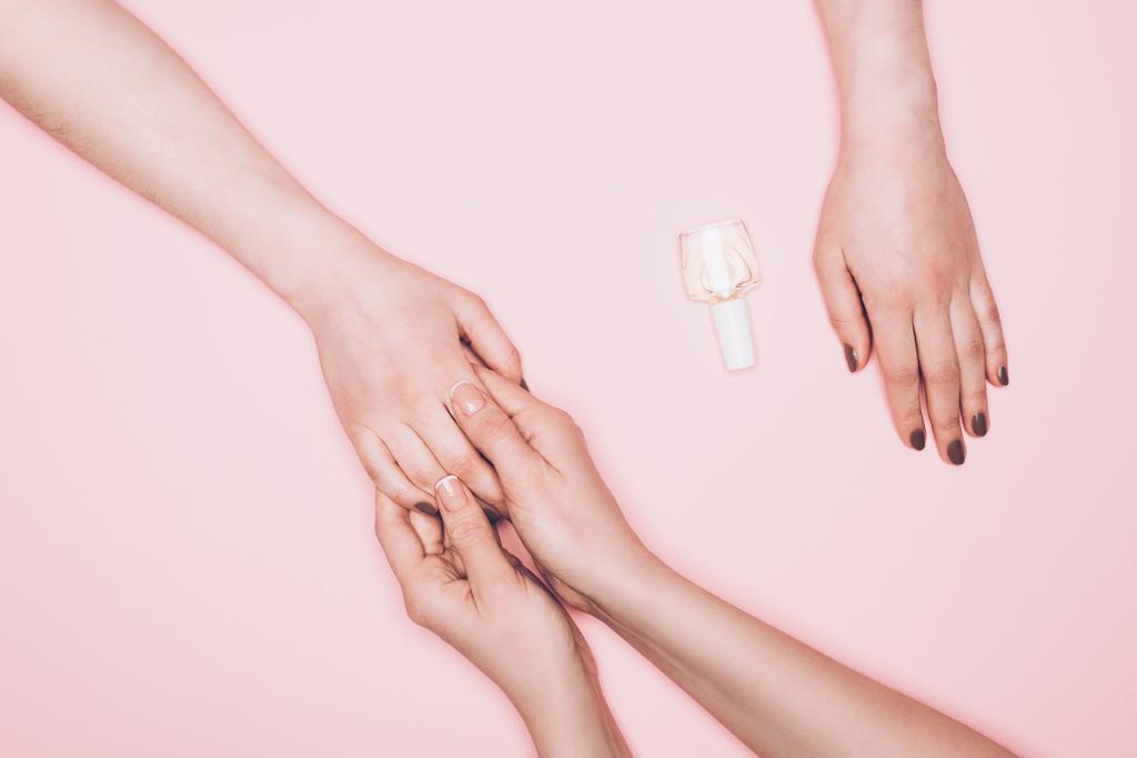 bijgesneden schot van manicure holdign hand van client geïsoleerd op roze - Foto, afbeelding