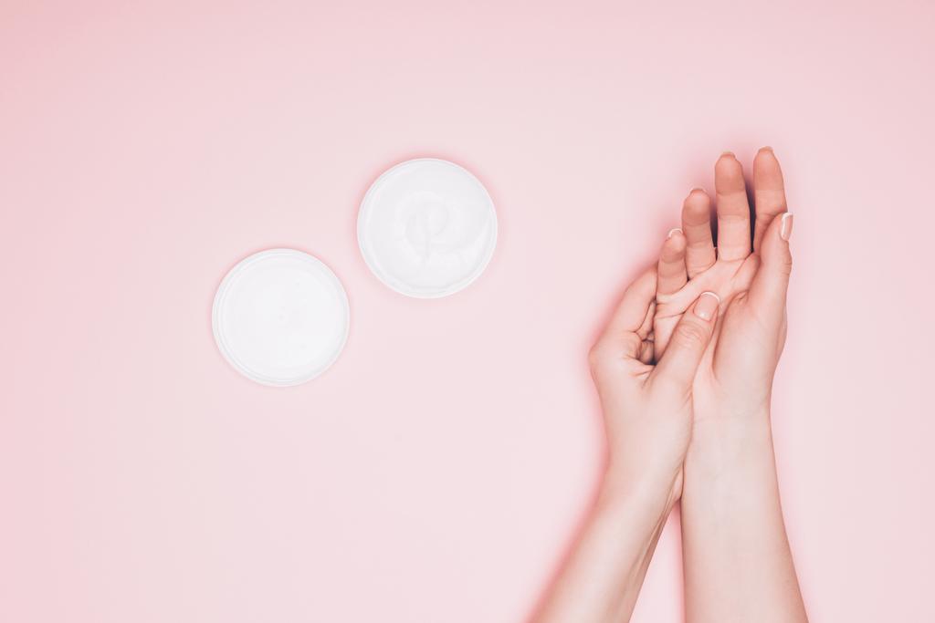 tiro recortado de la mujer aplicando crema hidratante en la mano aislado en rosa
 - Foto, imagen