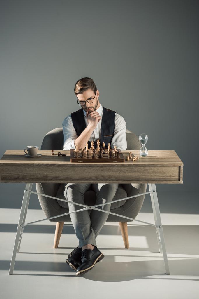 вдумливий молодий бізнесмен в окулярах грає в шахи
 - Фото, зображення
