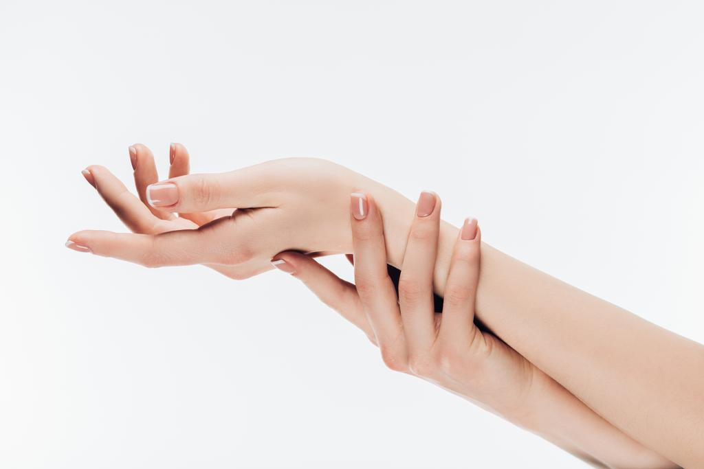 bijgesneden schot van vrouw met stijlvolle nagels toepassing hydraterende crème op handen geïsoleerd op wit - Foto, afbeelding