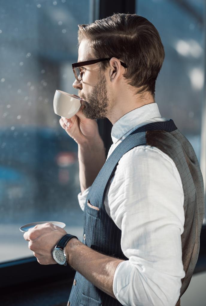 Porträt eines modischen jungen Geschäftsmannes mit Brille, der Kaffee trinkt  - Foto, Bild