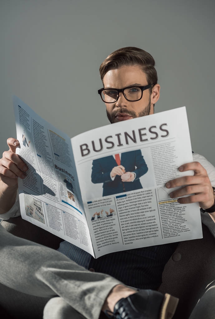 portrait de jeune homme d'affaires élégant dans des lunettes de lecture journal isolé sur gris
  - Photo, image