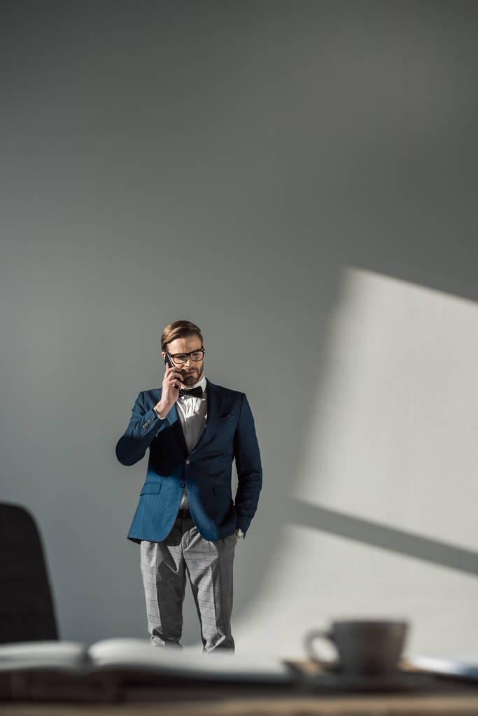 избирательный фокус стильного бизнесмена в очках и галстуке-бабочке, разговаривающего со смартфоном
   - Фото, изображение