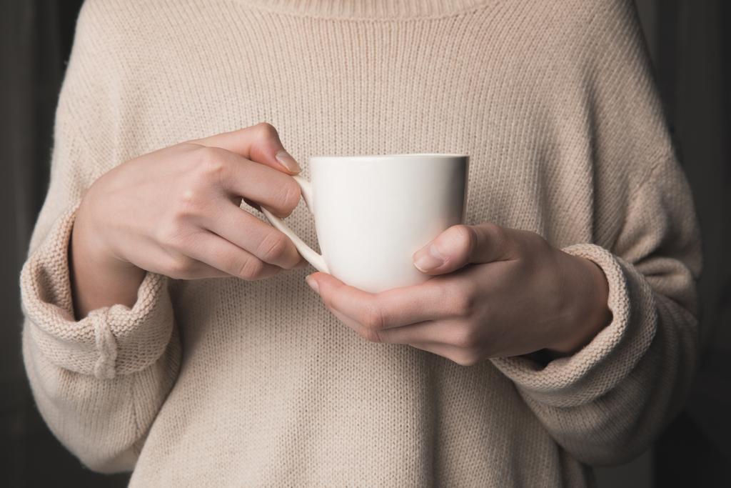 midsection de femme tenant muf de café dans les mains sur fond noir
 - Photo, image