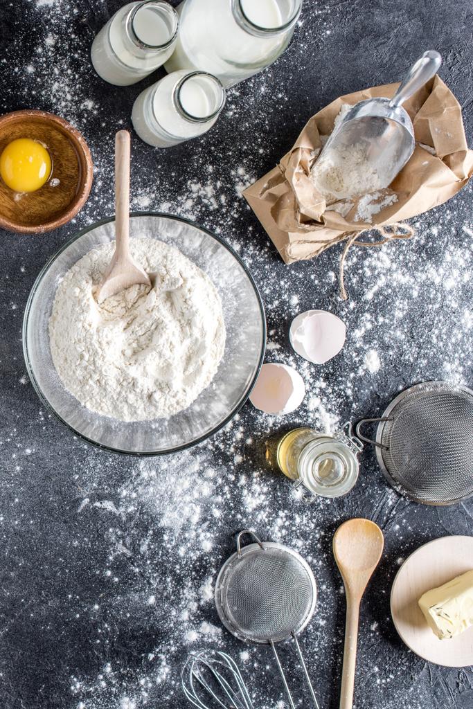 плоская укладка с мукой и другими ингредиентами для пекарни, кухонной утвари на темной столешнице
 - Фото, изображение