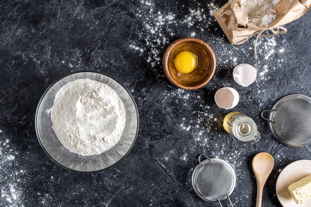 ylhäältä näkymä järjestetty keittiötarvikkeita ja ainesosia leipää leivontaan tummalla marmoripinnalla
 - Valokuva, kuva