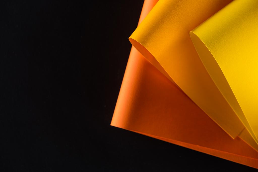 πορτοκαλί και το κίτρινο χρωματιστά χαρτιά που απομονώνονται σε μαύρο - Φωτογραφία, εικόνα