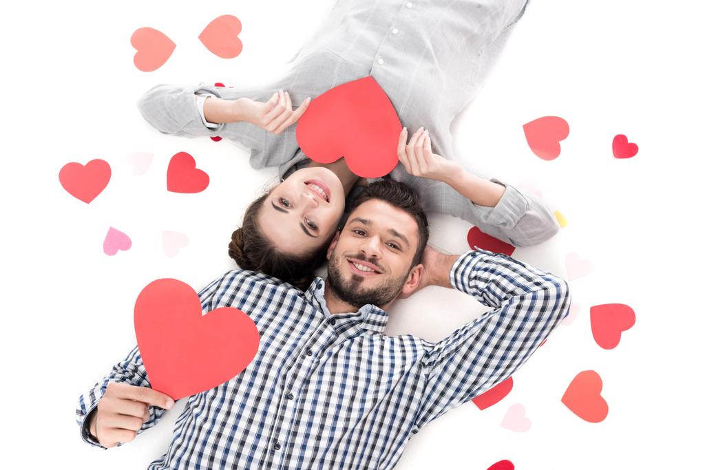 vista aérea de pareja acostada con corazones de papel aislados en blanco, concepto de día de San Valentín
 - Foto, imagen