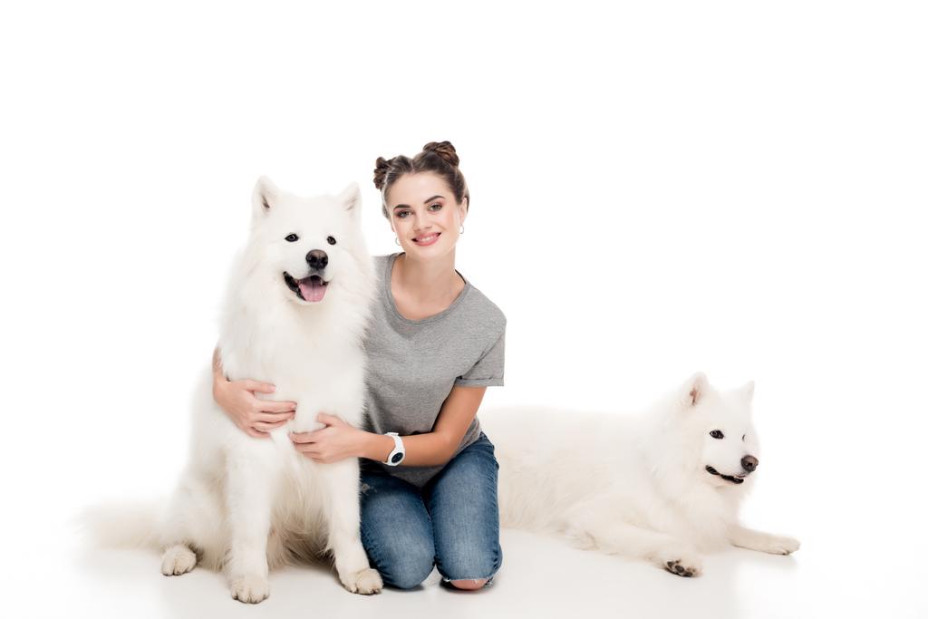 hymyilevä tyttö istuu koirien kanssa valkoisella
 - Valokuva, kuva