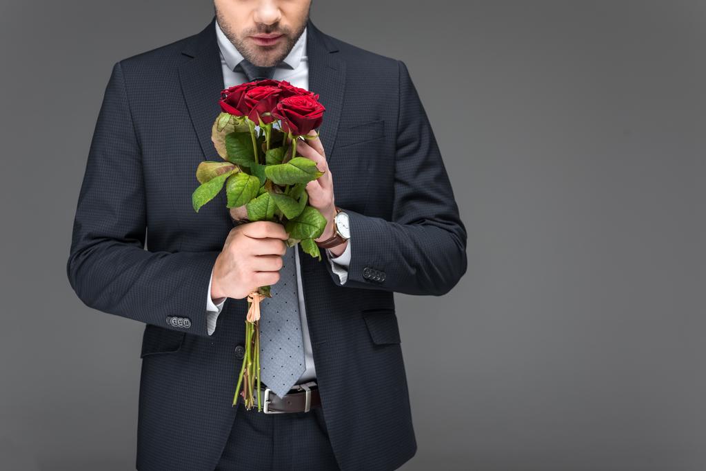περικοπεί άποψη του άνδρα να κρατάει μπουκέτο από κόκκινα τριαντάφυλλα, απομονώνονται σε γκρι - Φωτογραφία, εικόνα