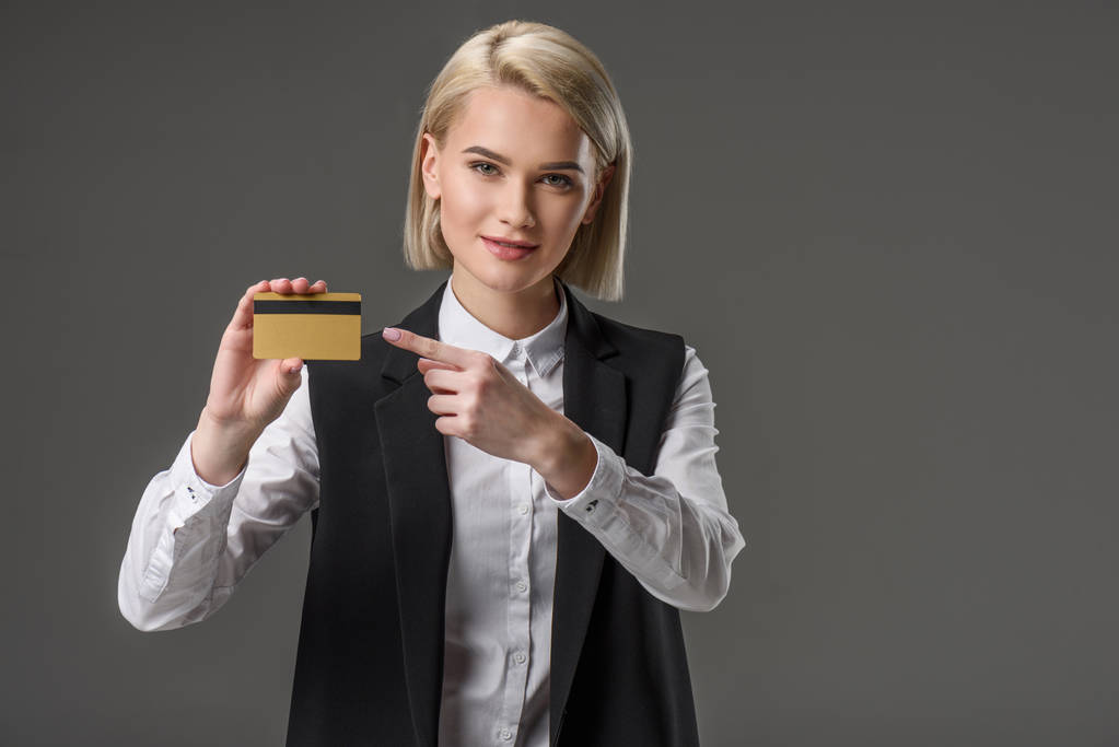 retrato de mujer apuntando a la tarjeta de crédito en mano aislada en gris
 - Foto, imagen
