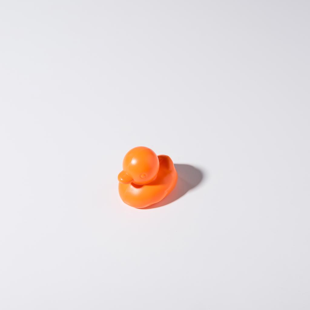Nahaufnahme einer orangefarbenen Gummiente isoliert auf grau - Foto, Bild