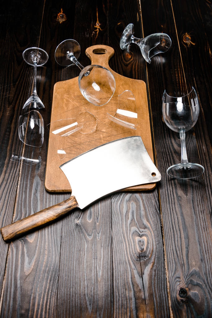 vista de alto ângulo de vidros quebrados e machado com placa de madeira na mesa
 - Foto, Imagem