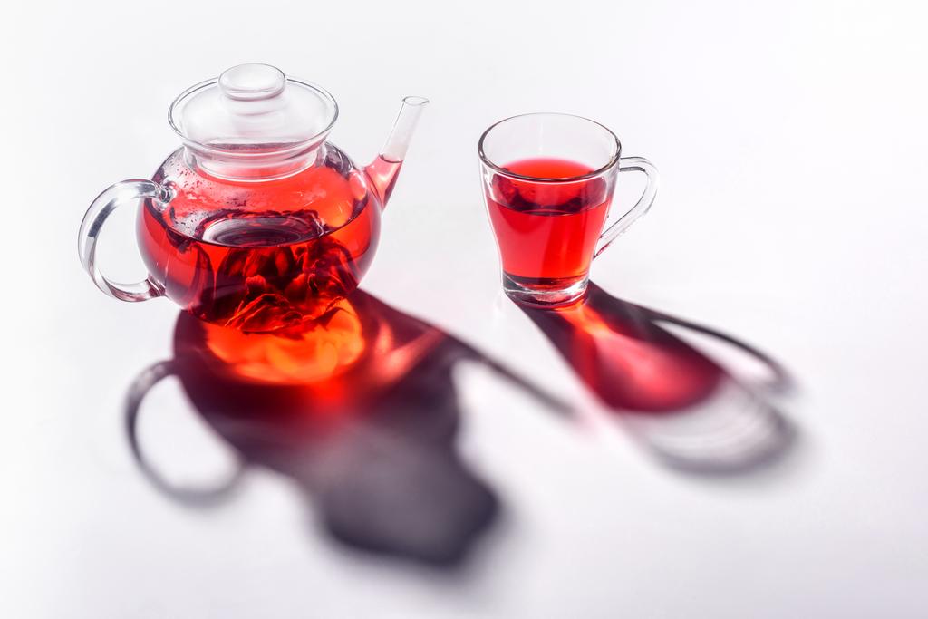 tetera de vidrio y taza transparente de vidrio con té de hibisco en la mesa
 - Foto, Imagen