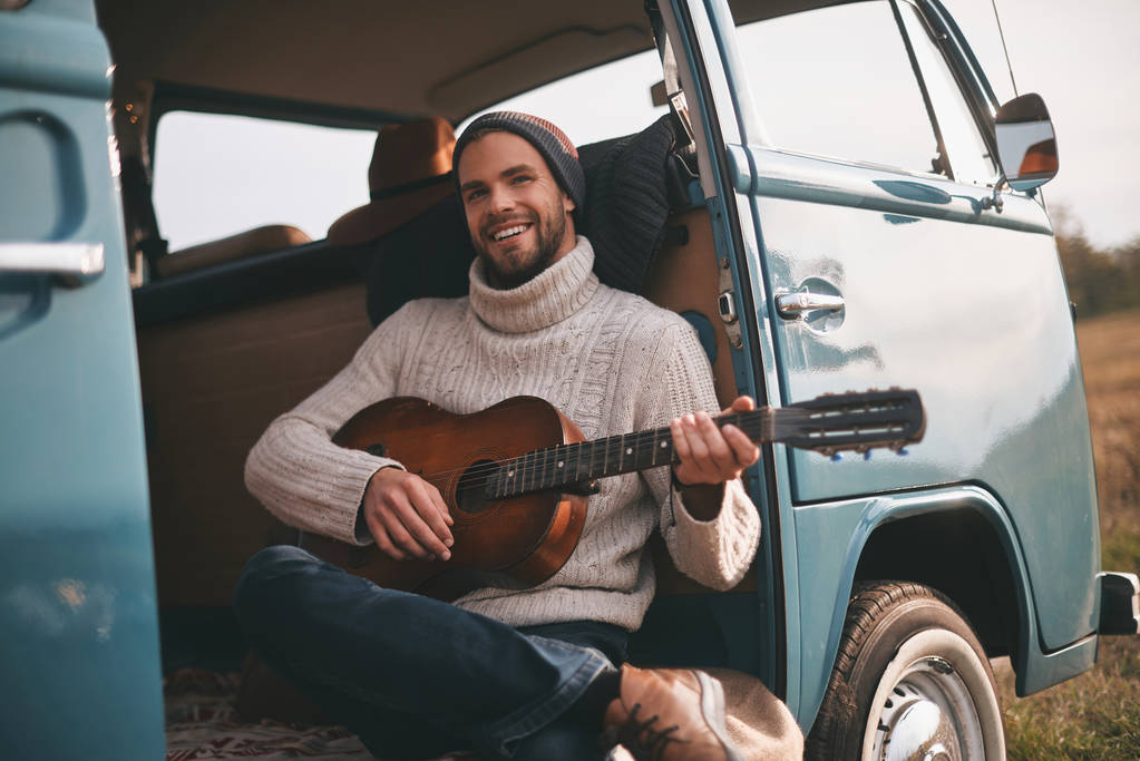 elegáns férfi játszik új dal, akusztikus gitár, az autó törzs - Fotó, kép