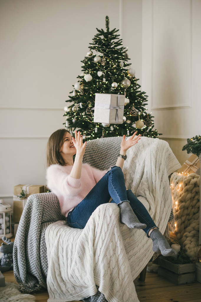 Nuori kaunis nainen istuu nojatuoli ja oksentaa joululahjaksi, sisätiloissa
 - Valokuva, kuva