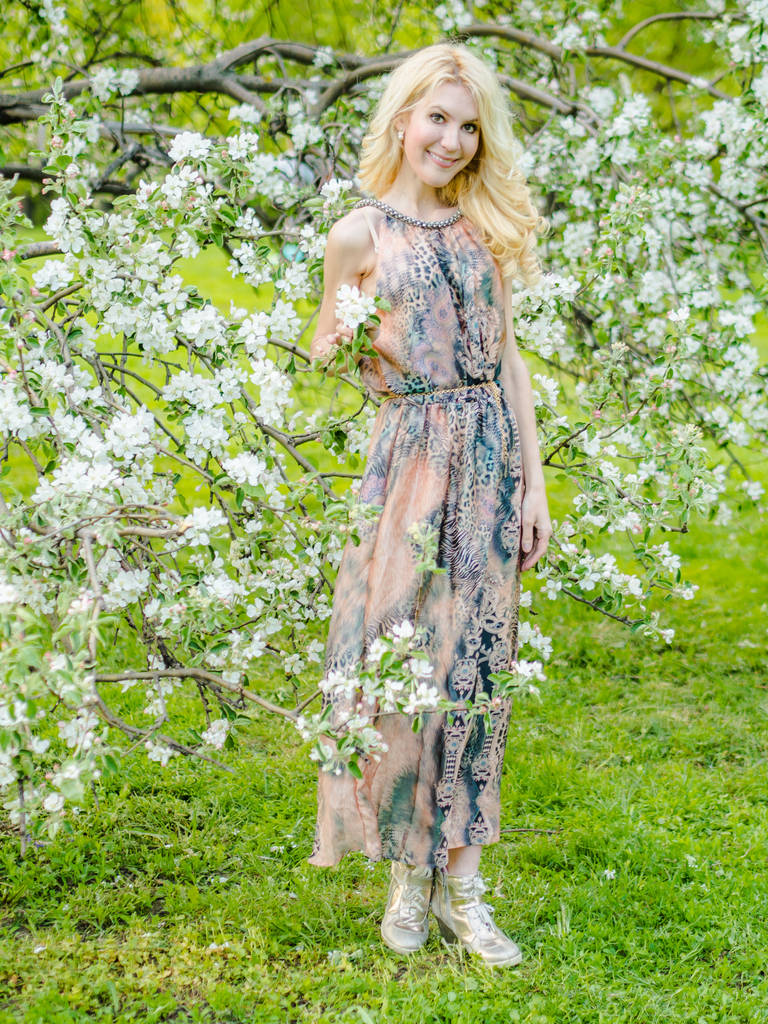 gyönyörű orosz lány-szőke egy hosszú nyári ruha, a háttérben egy virágzó almafa - Fotó, kép