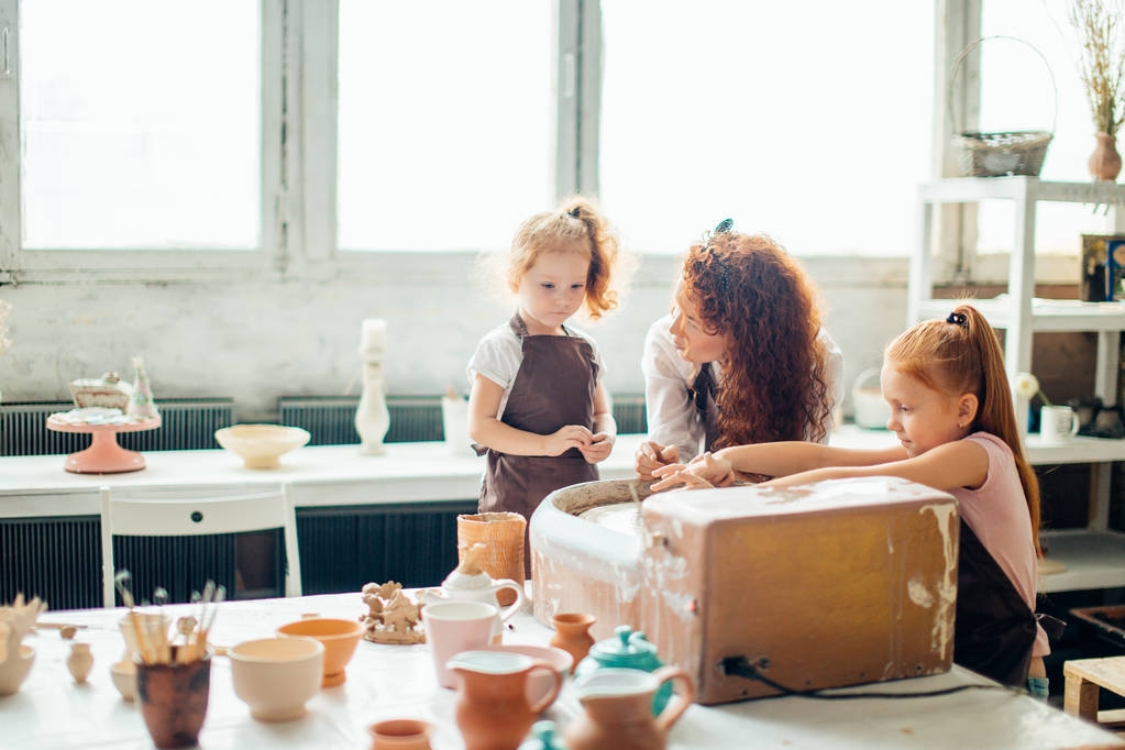 mother and two redhead daughters made clay cup with pottery wheel - Photo, Image
