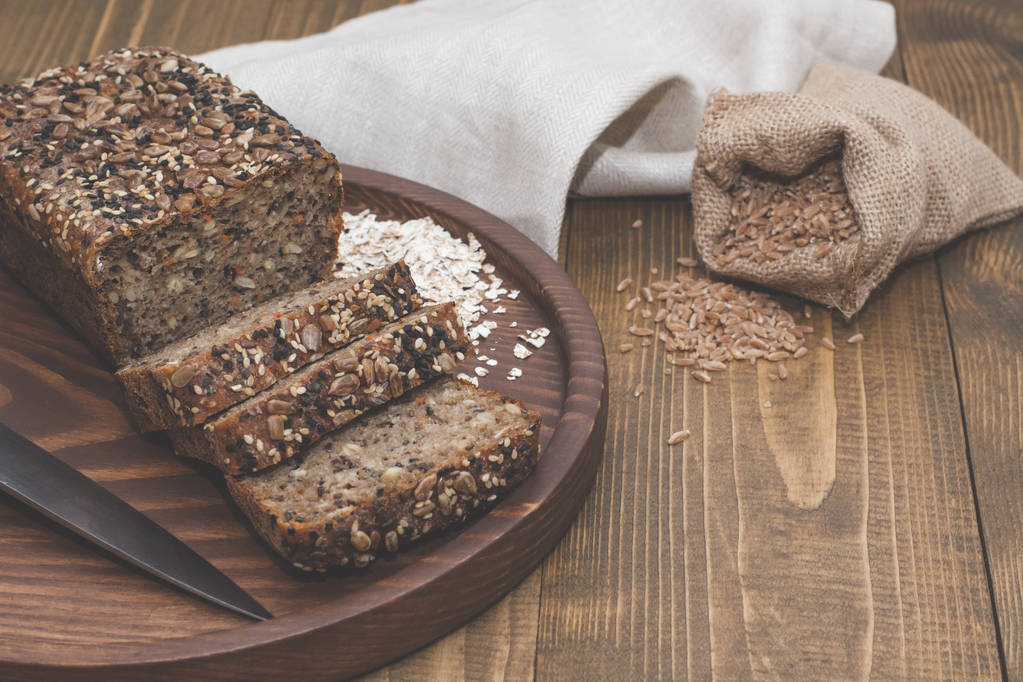Fitness bread. A loaf of fresh rustic whole meal rye bread, sliced on a wooden board, rural food background. Top view. Copy space. - Photo, Image