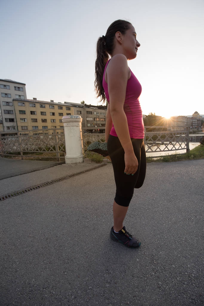 Athletin beim Aufwärmen und Dehnen während der Vorbereitung auf das Laufen auf der Stadtstraße am sonnigen Morgen - Foto, Bild