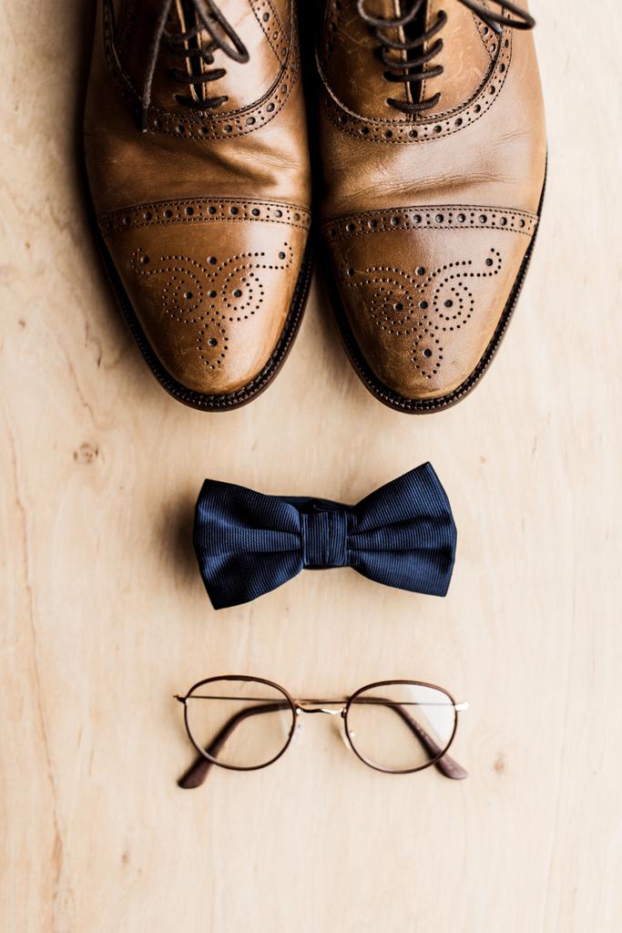 Ansicht von Schuhen, Fliege und Brille auf Holzboden  - Foto, Bild