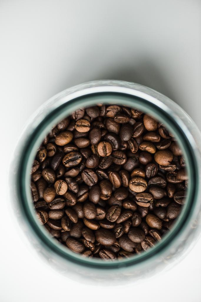 pohled shora na skleněné láhve s kávová zrna na bílém - Fotografie, Obrázek