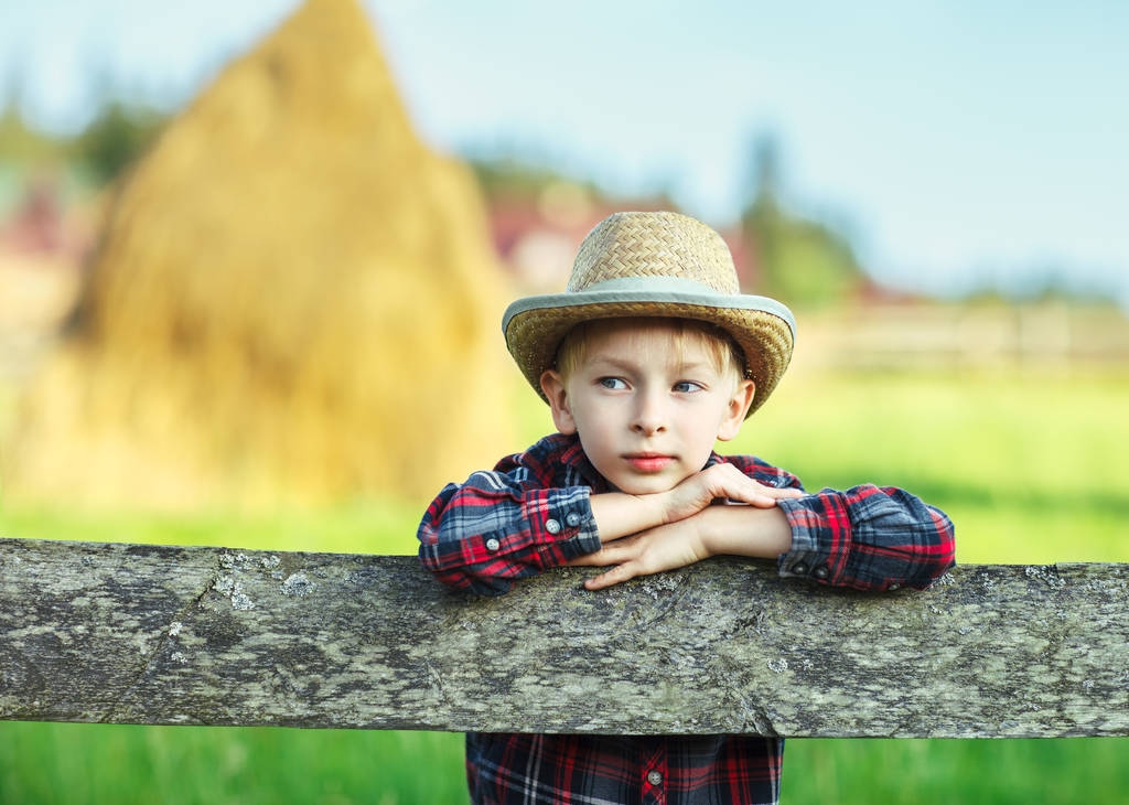 Close up portrait of handsome little boy in hat leaned on wooden fence. Happy chilhood concept. Vacation - Photo, Image